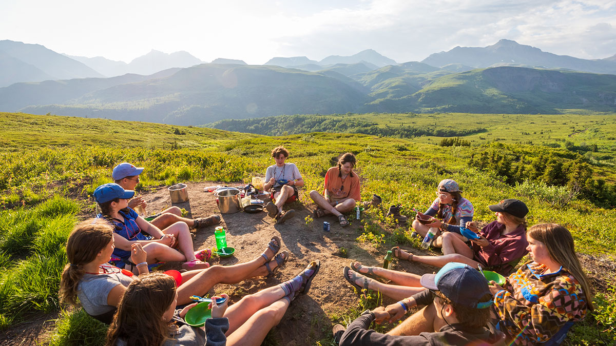 teenagers eating lunch on trail in alaska