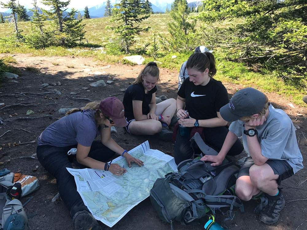 teenagers looking at a map while hiking in british columbia