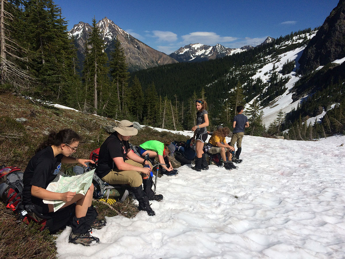 teenage boys and girls reading a map while hiking