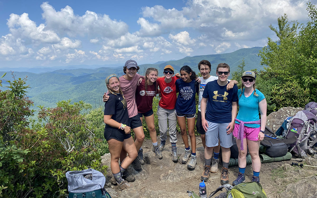 teenage boys and girls hiking with backpacks in the mountains