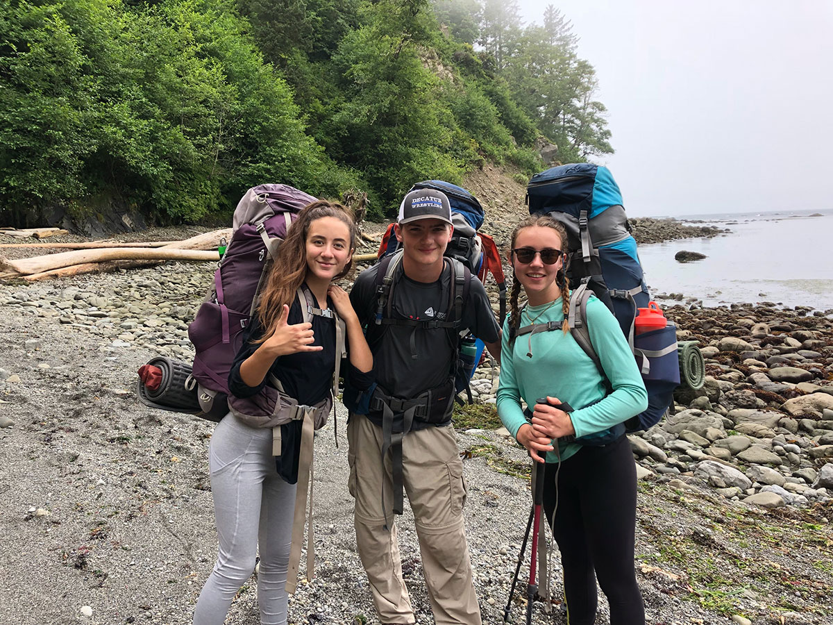 teenage boy and teenage girls backpacking on beach in washington